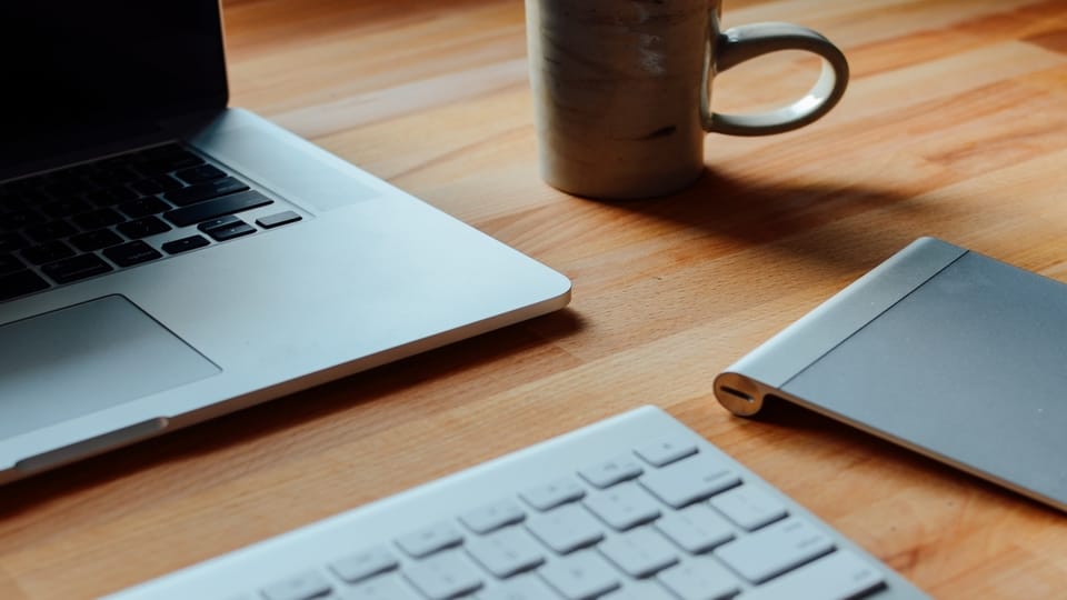 Apple-macbook-on-desk-with-keyboard-and-coffee-cup